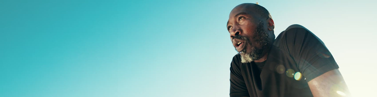 Man with a beard and tattoos on his arms against a blue sky